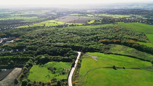 Aerial, Cinematic clip of a narrow road with earth moving trucks transporting aggregates from a quarry