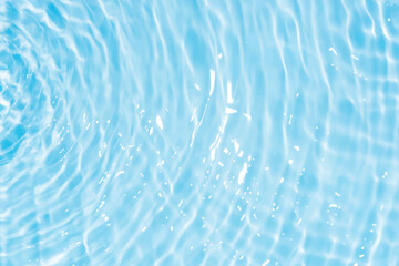 Blue water with ripples on the surface. Defocus blurred transparent blue colored clear calm water surface texture with splashes and bubbles. Water waves with shining pattern texture background.