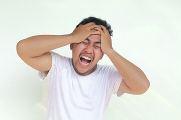Fototapeta premium A portrait of an Asian man wearing a white shirt isolated by gray background looks depressed.