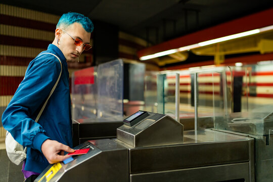 Man with blue hair entering subway station turnstile
