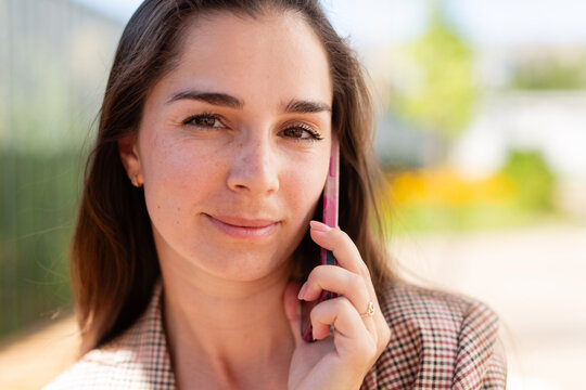 Woman talking on a pink mobile phone outdoors
