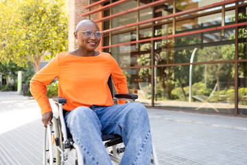 Confident black woman in wheelchair at modern office exterior