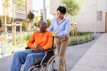 Professional woman assists colleague in wheelchair outdoors