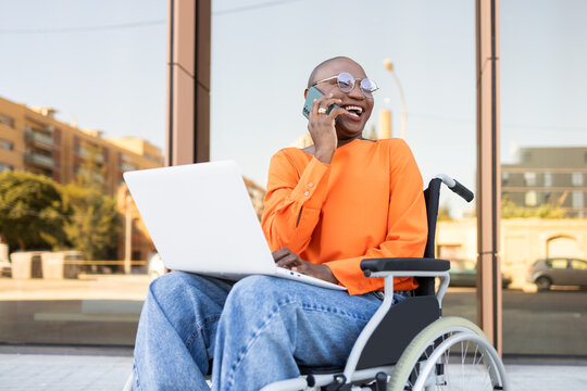 Cheerful businesswoman in wheelchair engaging with technology