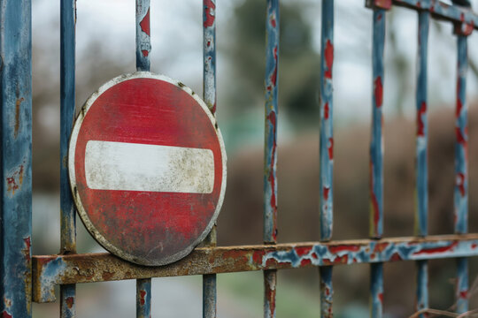 Old and worn no entry sign mounted on a rusting blue gate, symbolizing restriction and private property access denial