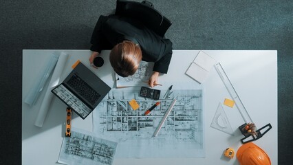 Top view of businesswoman look at blueprint. Engineer sit at meeting table with project plan, equipment and safety helmet. Aerial view of manager explain about building construction. Alimentation.