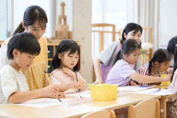 学童や放課後デイサービス等で勉強をする先生と生徒　小学生複数