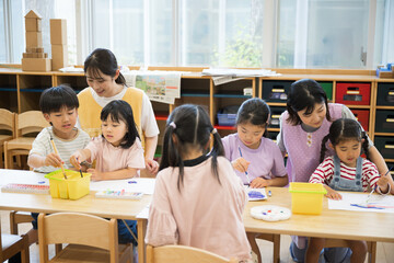 学童や放課後デイサービス等で勉強をする先生と生徒　小学生複数