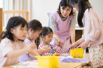 学童や放課後デイサービス等で勉強をする先生と生徒　小学生複数