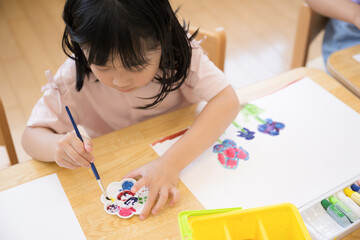 絵具で水彩絵を描く幼児の子供　女の子　幼稚園や保育園での様子　俯瞰