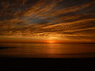 atardecer en el mar calmo con nubes pintadas por los rayos solares