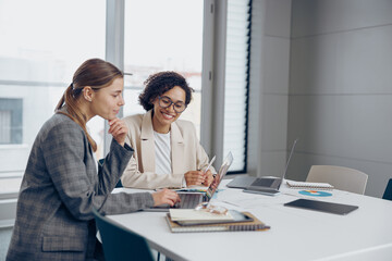 Obraz premium Female sales managers working on project together and use laptop sitting in office
