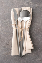 Set of stylish cutlery and napkin on grey textured table, top view