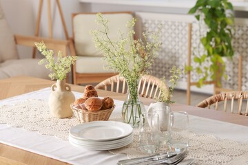 Clean dishes, flowers and fresh pastries on table in stylish dining room
