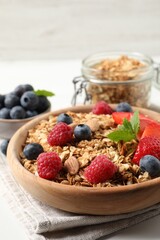 Tasty granola with berries, nuts and mint on white table