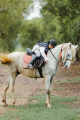 Portrait of Asia girl riding horse in the farm