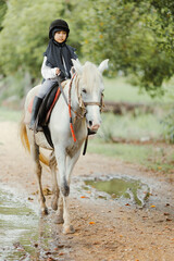 Portrait of Asia girl riding horse in the farm