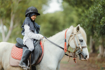 Portrait of Asia kid riding horse in the farm