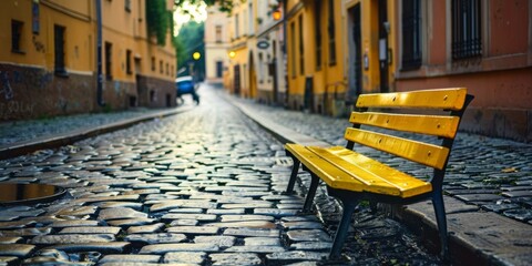 Fototapeta premium Lonely Yellow Bench on a European Cobblestone Street: A Serene Outdoor Scene Perfect for Travel, Solitude, and Lifestyle Reflections. High-Resolution AI-Generated Wallpaper Background.