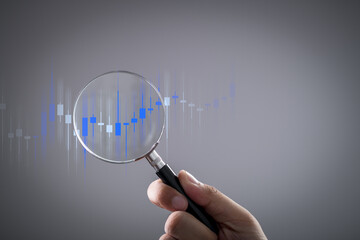 traders holding magnifying glass using technology for analysis of graph stock market trading. Financial investments and bank technology in the trading. Business growth, stock chart concept.