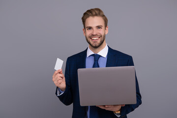 Businessman business man in suit showing credit or debit card to pay online on laptop isolated on grey