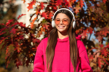 Enjoy autumn forest. Girl listen to music in headphones. Warm autumn. Girl with headphones outdoor....