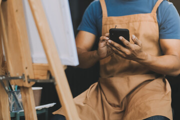 Young male artist painting picture in studio