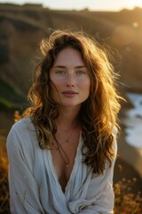 Obraz premium portrait of a young woman with sun-kissed skin on a windswept coastal cliff at golden hour