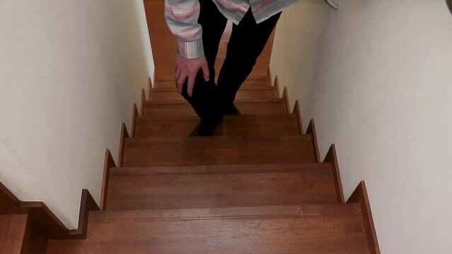膝を押さえながら階段をゆっくりと上る男性