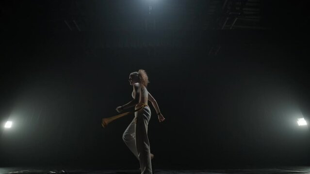 Capoeira fighters performing dynamic moves on stage. Martial arts, dance, and acrobatics in action. Bare-chested athletes showcasing strength, flexibility, and technique under spotlights