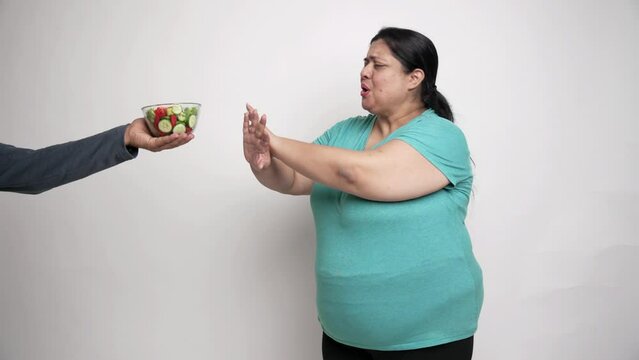 Overweight indian woman avoiding and say no to healthy salad food. Plus side female obesity problem, weight loss,