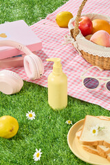 Creative photo template was taken from high angle for advertise cosmetic products manufactured from natural ingredients. The blank label bottle displayed on grass, pink picnic rug is spread in back