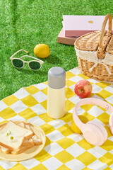 Picnic set up with yellow rug spread on green grass, displays a blank water bottle in center and...