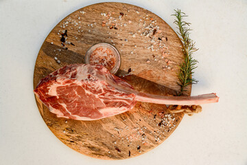 Tomahawk sobre tabla de madera con especias y hierbas aromáticas 