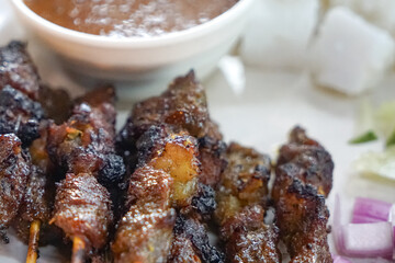 Close up view of satay (sate), a popular Malaysian street food.  Served together with peanut sauce, sliced cucumber, onion and rice cube (nasi impit)