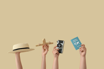 Female hands with passport, photo camera, hat and wooden airplane on beige background. Travel concept