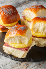 Ham and cheese sliders with a tropical twist a slice of pineapple closeup on the slate board on the table. Vertical