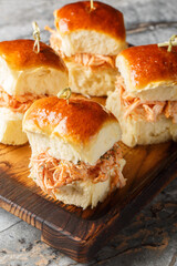 Homemade Hawaiian rolls with pulled chicken and cheese close-up on a wooden board on the table. Vertical