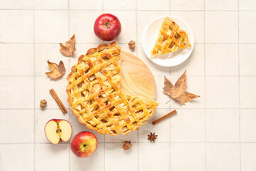 Wooden board with delicious apple pie and plate of piece on white tile background