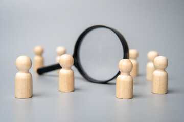 Obraz premium Wooden dolls and magnifying glass. Talent acquisition, recruitment and hiring concept.