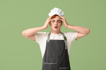 Shocked male confectioner in apron on green background