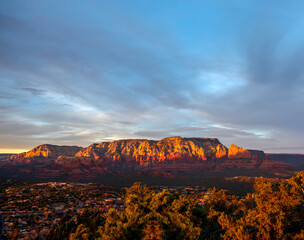 Wide panorama of rocky Sedona, Arizona canyons at sunset with dramatic twilight sky and wispy clouds.