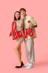 Young couple with air balloon in shape of word LOVE and rose flower on pink background. Valentine's Day celebration