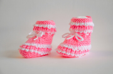 Pink knitted baby booties socks on white background