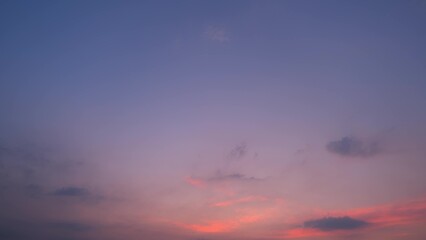 A tranquil sunset with the sky blending from soft purples and pinks to deeper blues. Wispy clouds are gently lit by the fading sunlight, creating a peaceful and calming atmosphere. Nature background.
