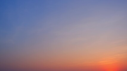 A beautiful sunrise with a gradient sky transitioning from deep blue at the top to soft pinks and oranges near the horizon. The sun is just beginning to rise, casting a warm glow. Nature background.
