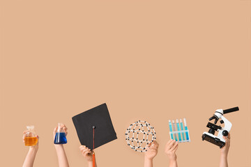 Female hands holding microscope with molecular model, filled test tubes and graduation hat on beige...
