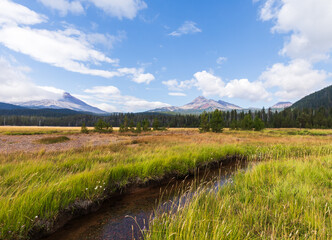 Scenic wide angle view of distant mountains and wispy white cloud sky in Sisters, Oregon, on a  sunny summer day.