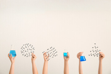 Female hands holding filled flasks with bottle and molecular models on white background. Chemistry...