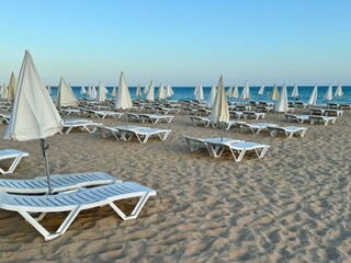 Empty sun beds and umbrellas on sea side. Empty sea beach, no people, end of season,